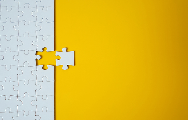 White jigsaw puzzle on yellow background. Team business success partnership or teamwork.