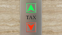 Engraved label TAX between up and down lift buttons on a marble wall. Illustration of the concept of tax and self assessment