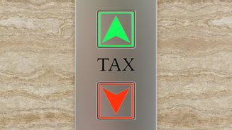 Engraved label TAX between up and down lift buttons on a marble wall. Illustration of the concept of tax and self assessment