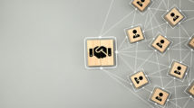 Hand shake icon on wooden cube block which connection with human icon for business deal and agreement concept.