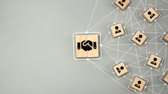 Hand shake icon on wooden cube block which connection with human icon for business deal and agreement concept.
