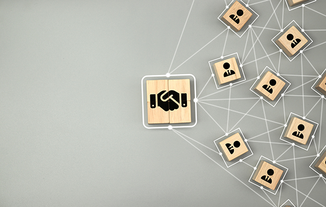 Hand shake icon on wooden cube block which connection with human icon for business deal and agreement concept.