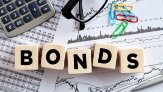 The word bonds on wooden cubes with office desktop. Business finance stock exchange concept.